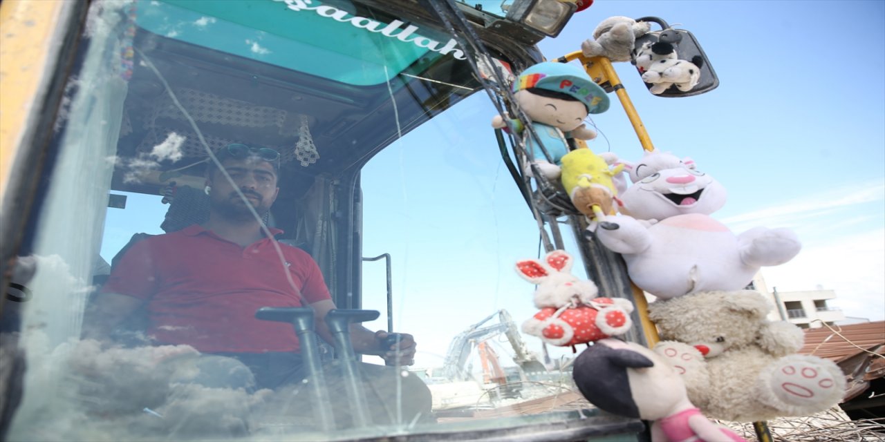 Kaldırdığı enkazlardan çıkan oyuncakları kepçesine asıp çalışmaya devam ediyor.